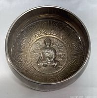 Top view showing inside of the bowl with a carved seated Buddha and lotus flower motifs around it.