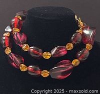 Front view of deep purple-red chunky tourmaline beads paired with smaller amber-colored beads, necklace displayed on black bust.