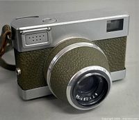 Front three-quarter view showing silver body, olive green covering, collapsible lens and flash port