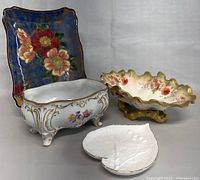 Four porcelain items arranged, showcasing heart-shaped bone china dish, rectangular floral plate, white decorative footed bowl, and large scalloped floral bowl with gold base.