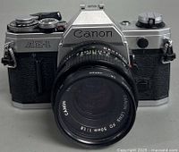 Front view of the Canon AE-1 with 50mm f/1.8 lens attached, showing camera markings and lens details