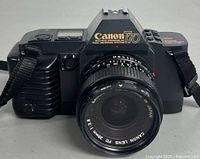 Front view of Canon T70 film camera with attached Canon FD 28mm f2.8 lens, showing camera body, lens glass, and strap.