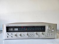 Front view, straight-on showing silver faceplate, control knobs and AM/FM tuner display