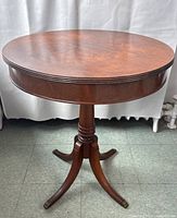 Front view of the round wooden pedestal table showing the top surface and leg design.