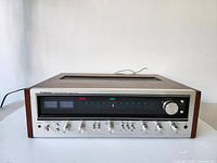 Front panel powered on, showing illuminated tuning scale, signal meters and control layout