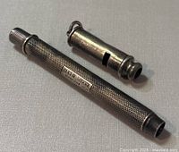 Photo of vintage S. Mordan Co mechanical pencil and silver whistle on a cloth surface.