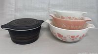 Photo showing side view of three nesting PYREX mixing bowls and Terra Brown lidded casserole dish