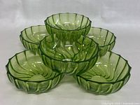 Six matching translucent green glass bowls by Federal Glass Co. stacked and arranged.