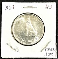 Front side of the 1967 Canadian silver 50 cents coin showing the howling wolf and inscriptions 'CANADA 1867-1967' and '50 CENTS' in AU condition.