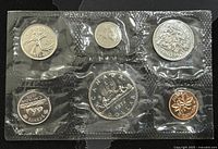 Photo of front side of six coins in sealed plastic packaging including all coin denominations and designs.