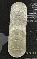 Stack of ten 1980 Canadian 1 Dollar coins showing the reverse with a canoe and two paddlers, clear date '1980' visible.