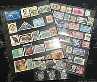 Photo showing two sheets filled with over 100 assorted postage stamps in various colors and designs, including portraits and animals.