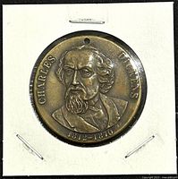 Front of the bronze Charles Dickens medallion showing detailed portrait and inscriptions.