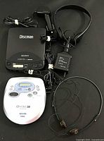 Full overview of the Sony and Sanyo portable Discman CD players with all accessories included in the lot: headphones and power adapters.