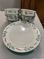 Eight Lenox Country Holly Chinastone dinner plates stacked with one plate shown from the front displaying holly leaf and red ribbon design border.