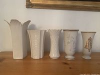 Front view of the five Lenox vases arranged side by side showing different shapes and embossed or painted floral patterns.