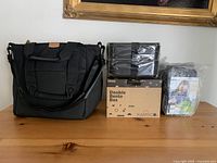 Photo of three items: a large black thermal lunch/drink bag, a boxed Double Bento Box by Karrice, and a plastic-sealed bento box.