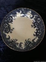 Single 10-inch porcelain dinner plate showing blurred soft blue transfer floral and scenic border on white background with gold-gilded rim.