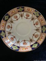 Top view of bone china saucer showing ornate floral and geometric gold-accented rim design.