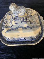 Closed covered vegetable dish showing Blue Willow pattern and dog figurine finial lid