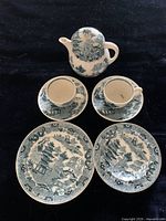 Full set view showing miniature teapot with lid, two cups, two saucers, two plates all in Blue Willow pattern on black background