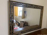 Full view of the rectangular wall mirror displaying the gold and black wooden frame and reflective mirror surface.