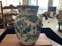 Photo shows a ceramic Bovey vase with a blue Persian floral pattern on a white base, depth of field focuses on vase with background blurred.