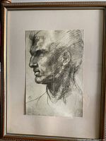 Framed graphite portrait sketch showing detailed male profile on paper.