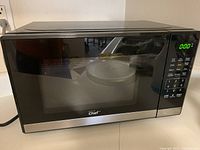 Front view of the Master Chef black and silver microwave oven, showing digital keypad, display, and door with viewing window.