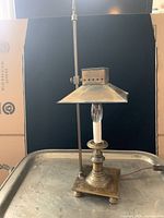 Front view of brass reproduction Paris Orient Express lamp showing base, lamp socket with bulb, and arrow finial.