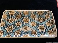 Top view of the rectangular ceramic plate with geometric and floral design in blue, brown, and yellow.
