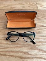Black computer glasses with clear lenses in front of open hard case with orange lining and AOSOMER branding.
