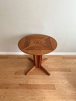 Front view of round teak patio table showing top pattern and base design
