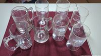 Full set of 8 glass drinkware pieces arranged on red cloth, showing 4 mugs and 4 stemmed glasses all bearing Lord Calvert Canadian logo.