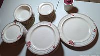 Top-down view of all dinnerware pieces arranged in stacks showing floral accents on ivory ceramic plates and bowls.
