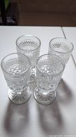 Top-down view of 4 clear cut glass goblets showing intricate cut glass pattern and footed bases.
