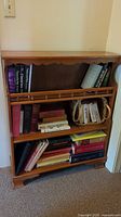 Front view of one wooden bookshelf filled with books and a basket on middle shelf.