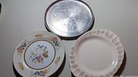 Lot with two porcelain plates and one oval metal tray on white background