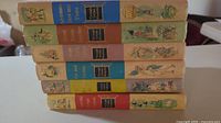 Stack of 5 hardcover children's books showing spines with titles and illustration in pastel colors.