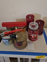 Photo showing assortment of jar candles, two red battery-operated Luminara pillar candles, and two Halo rechargeable candle lighters, one red one black, one new in box.