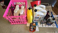 Photo showing various bottles of car fluids including Shell Rotella engine oil, Marvel Mystic Oil, antifreeze, Motor Medic, and more inside and outside of a pink crate.