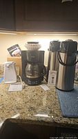 Photo of Mr. Coffee drip coffee maker, Proctor Silex electric can opener, Cook's Essentials electric jar opener, and two Bakers & Chefs airpots on kitchen counter