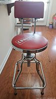 Front view of red Craftsman adjustable stool with padded seat and backrest, metal frame, and footrest.