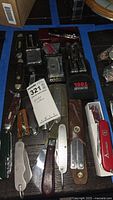 Full overview of assorted cutters on table including pocket knives and multi-tools