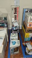 Photo showing multiple boxed vintage vehicle banks and diecast cars, including Linker Bank and boxed Buick model.