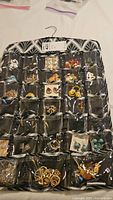 Black hanging organizer with many compartments holding assorted pairs of earrings in different colors, shapes, and styles
