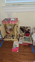 Overview of wardrobe dresser, boxed accessories, two dolls in boxes, and vintage brochure on floor