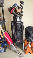 Wide view of Acuity golf bag with multiple golf clubs and headcovers inside next to shelf with other items