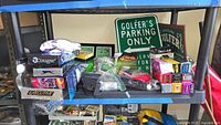 Shelf with boxed golf balls, golf signs, golf ball retriever, accessories, and gloves visible.