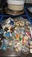 Photo showing a large pile of assorted pins including packaged and loose pins on a table.